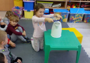 Dziewczynka trzymająca lusterko nad parującą wodą z czajnika.